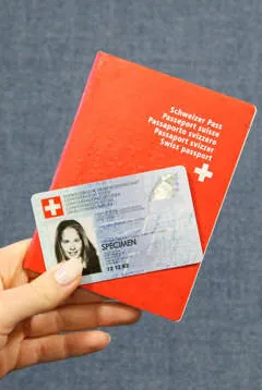 main qui tient une carte d'identité ainsi qu'une passeport suisse